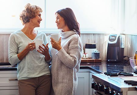 young woman talks with her mother over coffee in the kitchen