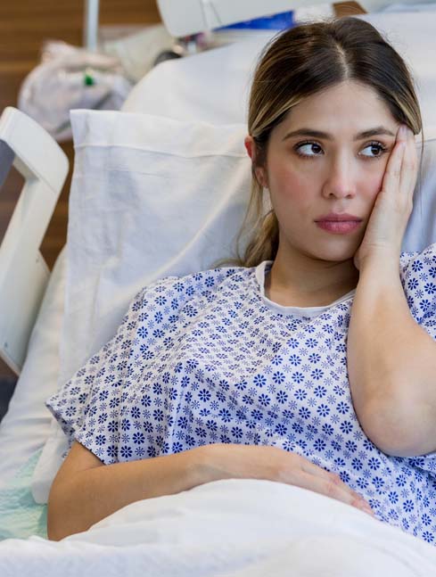 sad pregnant woman in hospital bed waiting to give birth